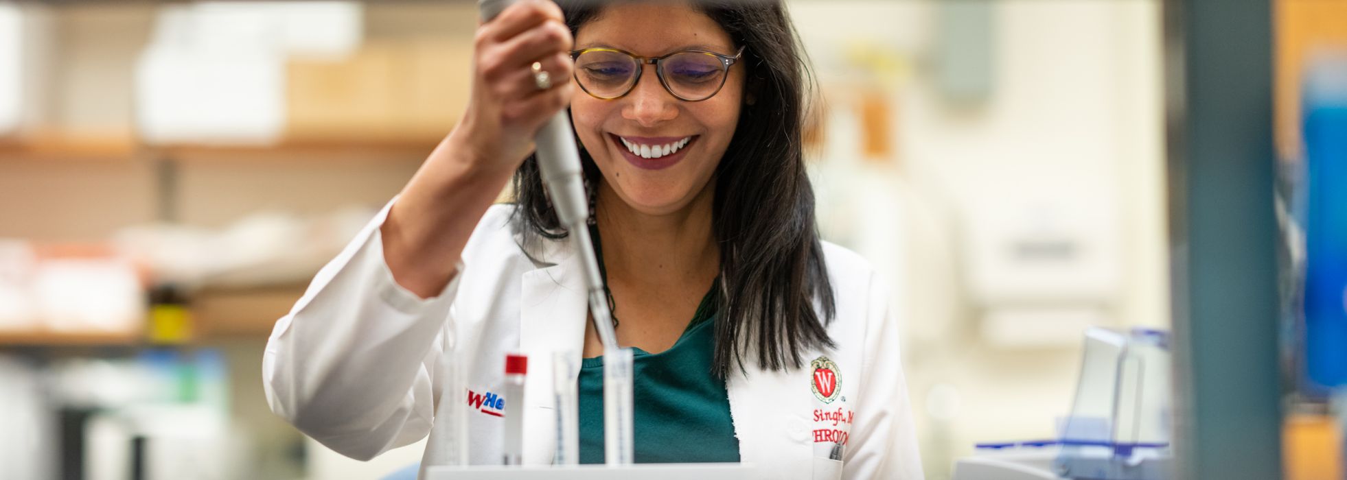 Dr. Tripti Singh wearing a white coat working with a pipette in the lab 