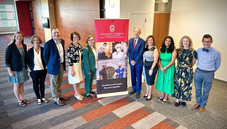 Department of Medicine faculty posing next to a Department of Medicine banner.