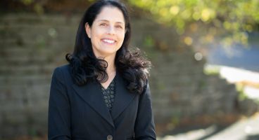 Dr. Lisa Strate, a Caucasian female with dark brown hair, wearing a navy blue blazer, smiling