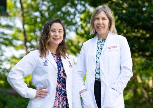 Lydia Buzzard and Sarah Ahrens stand outside wearing their white coats