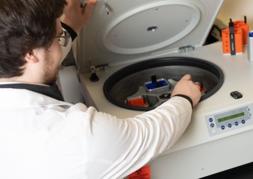A clinical research coordinator loads a centrifuge in a nephrology lab